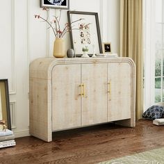 a white cabinet sitting on top of a hard wood floor next to a window with curtains