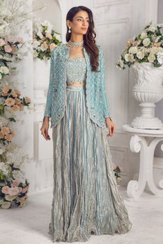 Modernize your wardrobe with this stylish Jacket outfit, cut from Pure raw silk featuring botanical embroidery in silver & antique gold with dabka, nakshi, sequins, zari, pearls, crystals and resham work. Heavily embellished bodice in shades of silver with scalloped beaded tassel details adds a modern touch to this outfit. Paired with shimmer tissue crushed lehenga & dupatta trimmed with lace details, this piece is one for the ages and timeless season and season again Jacket Fabric: Pure 80gms R Festive Designer Hand Embellished Choli, Festive Hand Embellished Party Choli, Hand Embellished Georgette Choli For Eid, Hand Embellished Anarkali Raw Silk Set, Elegant Anarkali Set With Sequins In Chinon, Elegant Anarkali Set With Sequins, Traditional Front Open Embellished Sets, Traditional Embellished Front Open Sets, Elegant Embellished Front Open Sets