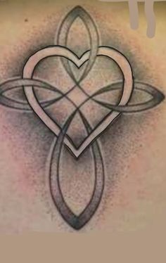 the back of a woman's shoulder with an intricate heart and cross tattoo on it