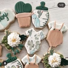 decorated cookies are arranged in the shape of cactuses and sweaters, with words baby on them