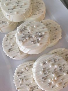 four cookies with pearls on them sitting on top of a white table covered in icing