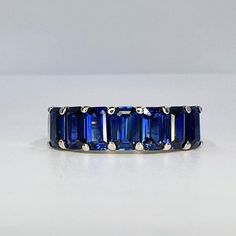 "The ring is lab created blue sapphire  #6221 This ring can be made with many different stone colors Message us for pricing on different color/type stones -Approximate total carat weight:  1.90ctw diamond equivalent  for more blue sapphire rings click here: https://etsy.me/3c9qrSN for blue sapphire earrings click here:  https://etsy.me/3AInVgz For blue sapphire pendants click here: https://etsy.me/3SC1sZ9 -Stone Size:  5x3mm - approx. 0.27ct each diamond equivalent  -Stone Shape: emerald cut 7 s Blue Sapphire Wedding Band, September Birthstone Ring, Blue Sapphire Earrings, Blue Sapphire Pendant, Ring Emerald Cut, September Birthstone Rings, Sapphire Wedding Band, Sapphire Rings, Sapphire Band