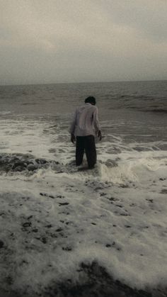 a man standing in the ocean with his surfboard