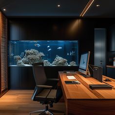 an office desk with a monitor and keyboard on it in front of a fish tank