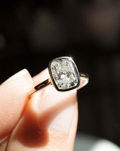 a close up of a person's hand holding a ring with a diamond in it