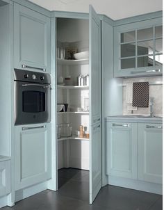 a kitchen with blue cabinets and an oven in the corner, is shown from the doorway