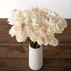 a white vase filled with lots of white roses