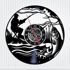 a wall clock with a fishing scene on the front and side of it in black