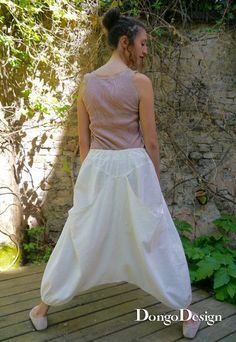 a woman standing on a wooden deck wearing a white skirt