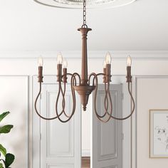 a chandelier hanging from the ceiling in a room with doors and potted plant