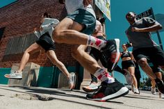 several people are running on the street with their feet in the air and one person is wearing sneakers