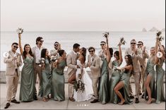 a group of people standing next to each other near the ocean with their arms in the air