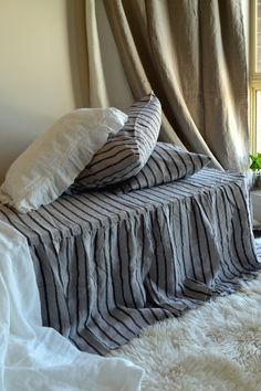 a bed with two pillows on top of it next to a white rug and window