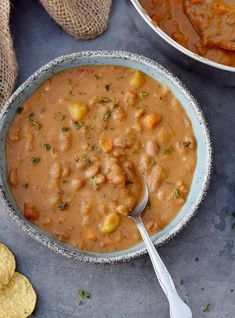 two bowls filled with soup on top of a table next to crackers and bread