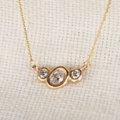 Organically sculpted 3 stone necklace, with one larger oval cut diamond and 2 small round diamonds on either side, bezel set in 14k yellow gold. 6x4mm Lab diamond Center / 3mm Lab diamond sides Total carat weight: .57ct Lab grown Diamonds Color: GH // Clarity VS2 Set on a 16"-18" adjustable 14KY chain Oval Cut Diamond, Three Stone, Lab Diamonds, Bezel Setting, Stone Necklace, Oval Cut, Jewelry Care, Lab Grown, Colored Diamonds