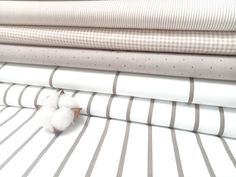 three small white birds sitting on top of striped sheets in front of a bed sheet