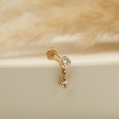 a pair of gold earrings with white stones on them sitting on a fur covered surface