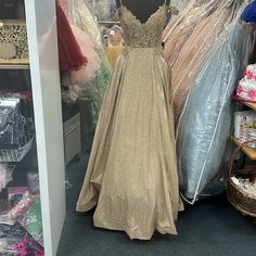 there is a dress on display in the closet with other clothes and dresses behind it