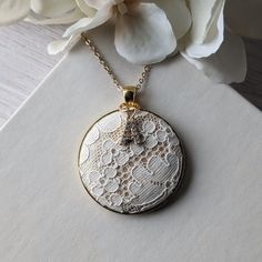 This vintage lace necklace is the perfect gift for those that love a timeless and elegant style. The white floral lace from the 1950s evokes a sense of delicate beauty, with a background of shiny gold satin that highlights the intricate lace design. It's set in a gold metallic metal alloy pendant, with a dainty gold stainless steel chain that measures 22 inches in total length. Letter charm: The finishing touch is the capital letter initial charm that adorns the top of the pendant. This charm offers the perfect way to make this necklace a thoughtful and personalized gift. Gift box: The necklace will be packaged in a stylish, branded gift box, ready to be presented with love and care.  Gift notes:  Write a personalized note to your loved one at checkout, and it will be printed on decorative Elegant Vintage Charm Necklace For Anniversary, White Lace Necklace For Wedding, Delicate White Round Bridal Necklace, White Filigree Round Pendant Necklace, White Victorian Wedding Necklaces, Victorian White Wedding Necklaces, Delicate White Bridal Necklace For Anniversary, Victorian White Wedding Necklace, White Vintage Necklace With Vintage Charm