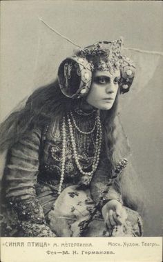 an old black and white photo of a woman with long hair, wearing elaborate headdress