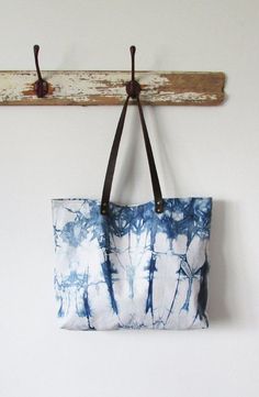 a blue and white tote bag hanging from a wooden hook on a wall next to a pair of scissors