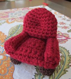 a crocheted red chair sitting on top of a table