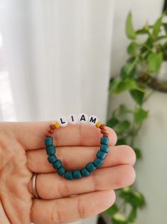 a hand holding a beaded bracelet with the word mia on it