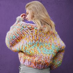 a woman wearing a multicolored sweater and checkered skirt with her back to the camera