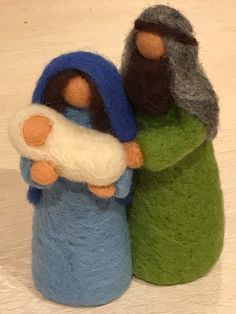 two needled nativity figurines, one holding a baby jesus