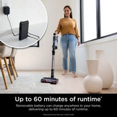 a woman standing next to a window holding a vacuum