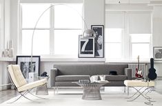 a living room filled with furniture next to a large window covered in white curtains and framed pictures