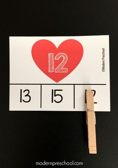 a red heart is on top of a white paper with the number twelve and an arrow