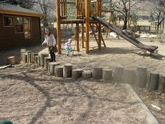 a young child playing in the sand at a park with a wooden structure and slide