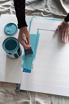 someone is painting on a white board with blue paint