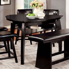 a dining room table with four chairs and a bowl of fruit on the counter top