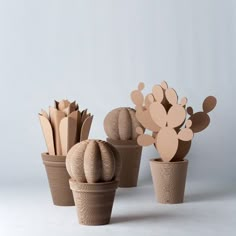 three potted plants made out of cardboard are sitting next to each other on a white surface