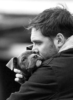 a man holding a small dog in his arms