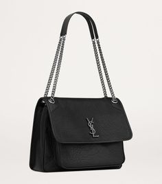 Find SAINT LAURENT Leather Niki Bag on Editorialist. The Niki bag is a structured shoulder bag featuring a flap closure with a turn lock. The bag features a top handle and a detachable chain strap. The Saint Laurent logo is embossed on the front flap. The bag is crafted from textured leather. Saint Laurent Niki Bag, Leather Saddle Bags, Classic Bags, The Saint, Logo A, Trainer Boots, Shoes Heels Pumps, Vintage Inspired Design, Leather Shops