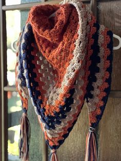 an orange, white and blue crocheted scarf hanging from a hook