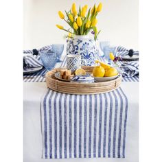 a blue and white striped table cloth with yellow tulips in a basket on it