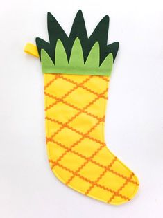 a pineapple shaped christmas stocking with green and yellow trimmings on it