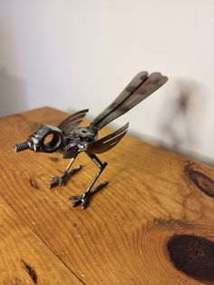 a metal bird sitting on top of a wooden table