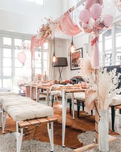 a room filled with lots of white furniture and balloons hanging from the ceiling above it