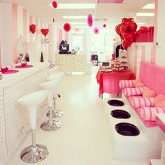 a room filled with lots of white furniture and pink decorations on the walls, along with balloons