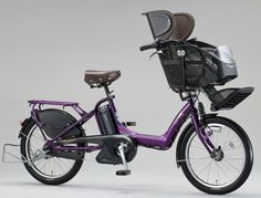 a purple bicycle with a basket on the front and back wheel, parked against a gray background