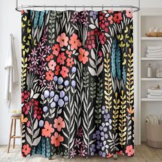 a shower curtain with colorful flowers and leaves on it in a white room next to bookshelves