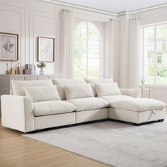 a living room with a white couch and large rug on the floor in front of two windows