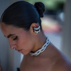 a woman with ear rings on her neck looking down at her cell phone while wearing a black and white dress