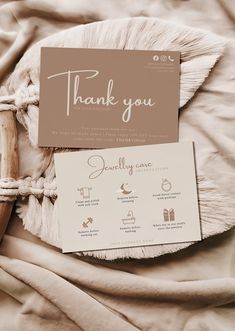 a thank you card sitting on top of a bed next to a wooden stick and rope