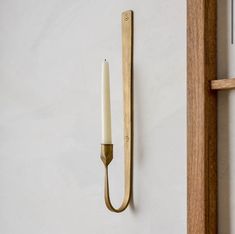 a candle is hanging on the wall next to a wooden door handle with a hook